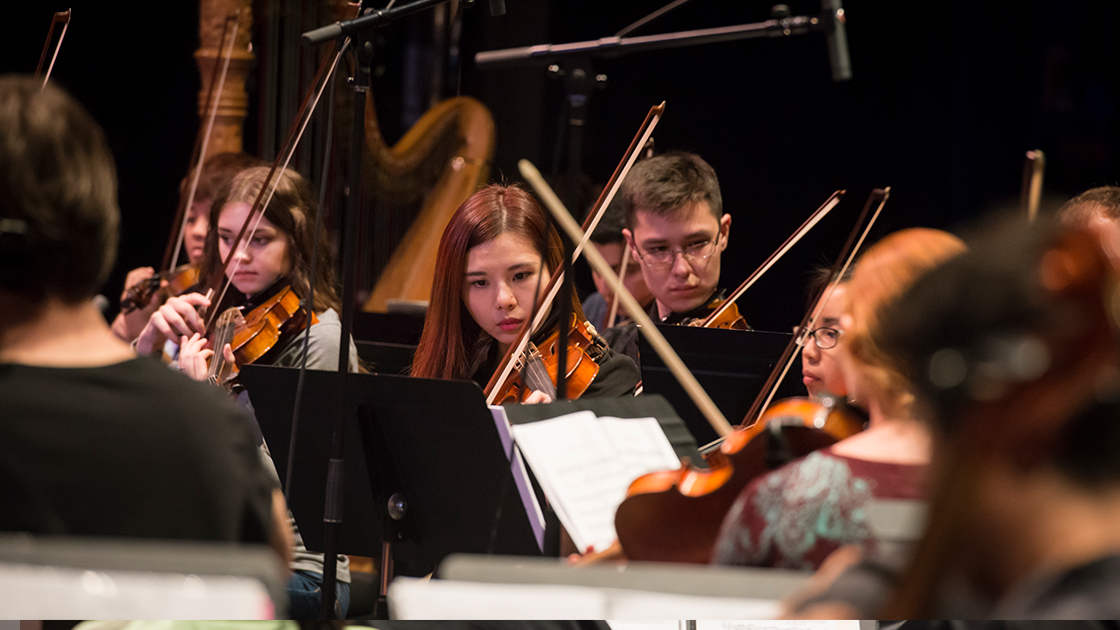 Orchestra rehearsal scene.