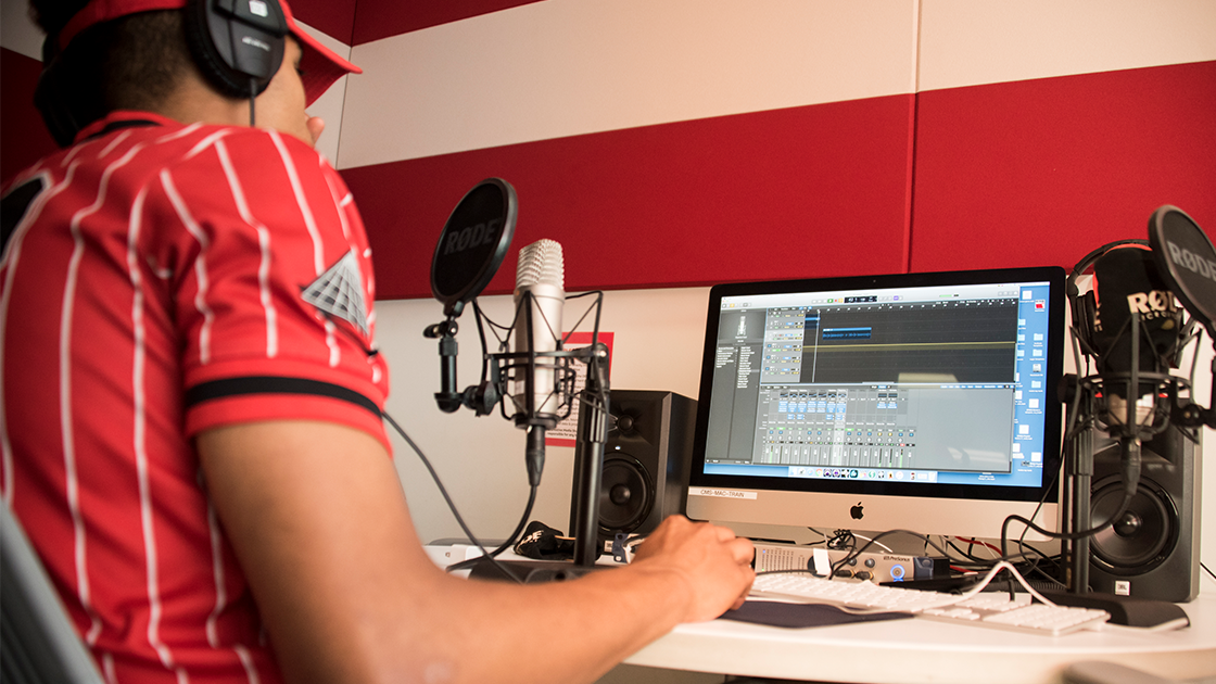 tudent records audio using a microphone and computer in CSUN’s music production studio.
