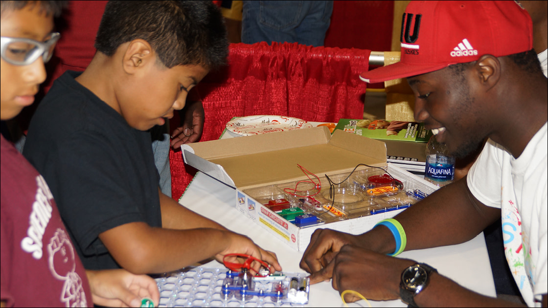 Kids learn about circuits from an NIU student at STEM Fest