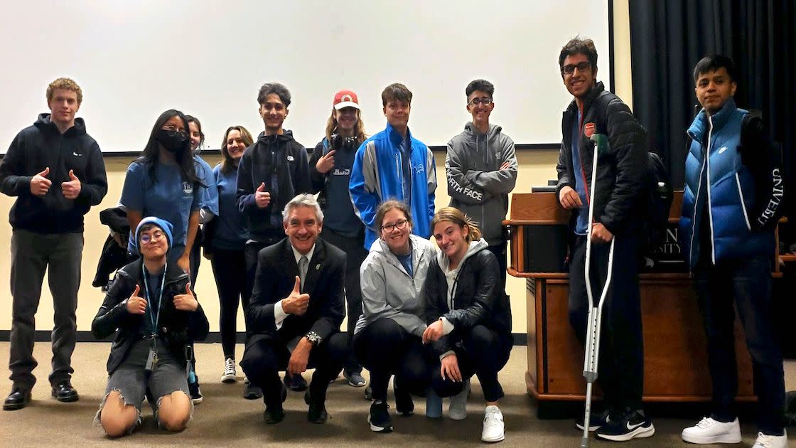 Honors College students posing and giving a thumbs up while they gather at the front of a classroom.