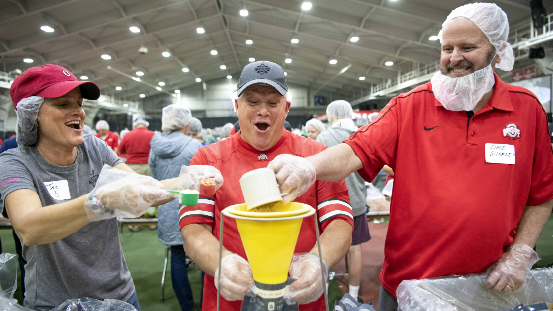 3 people in Ohio State clothing mixing ingredients in a funnel