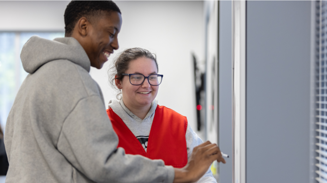 2 students drawing and looking at whiteboard