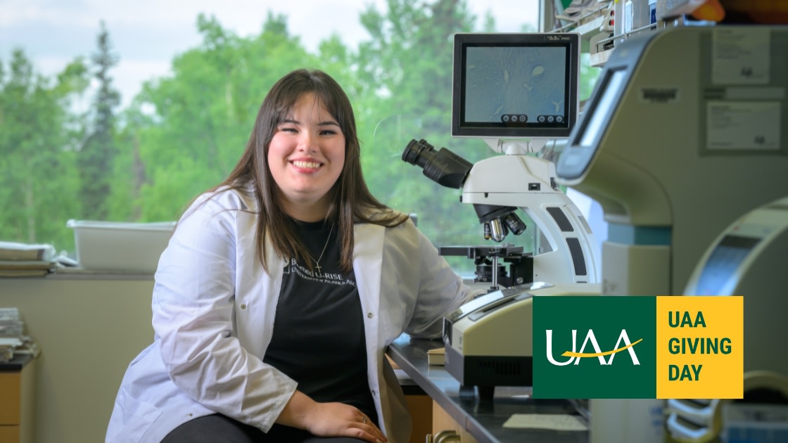 UAA Biology Major at a microscope in a lab.