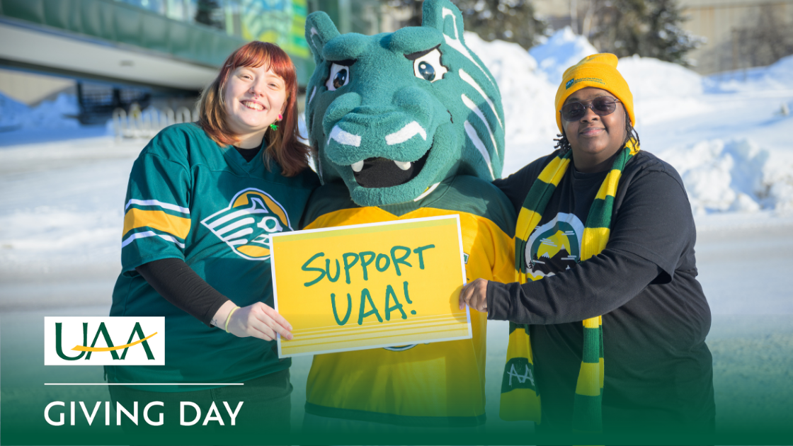 UAA students posing with Spirit the Seawolf on campus holding a sign that says, “Support UAA!”