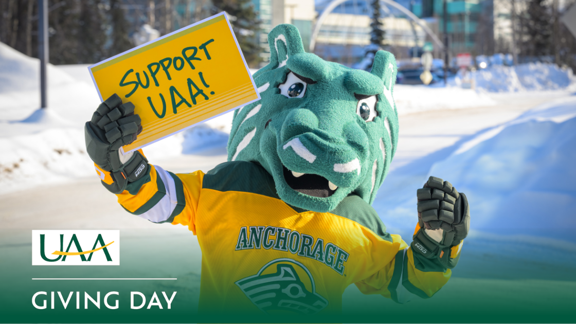 Spirit the Seawolf posing on campus holding a sign that says, “Support UAA!”
