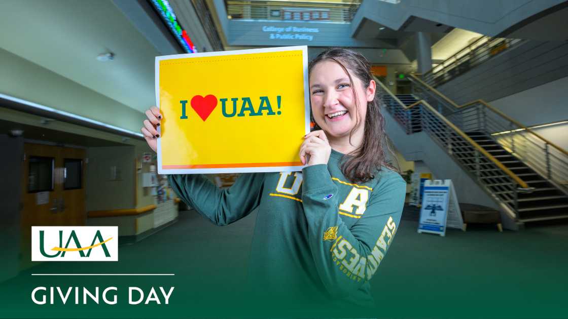 UAA student posing with a “I ❤️UAA!” sign