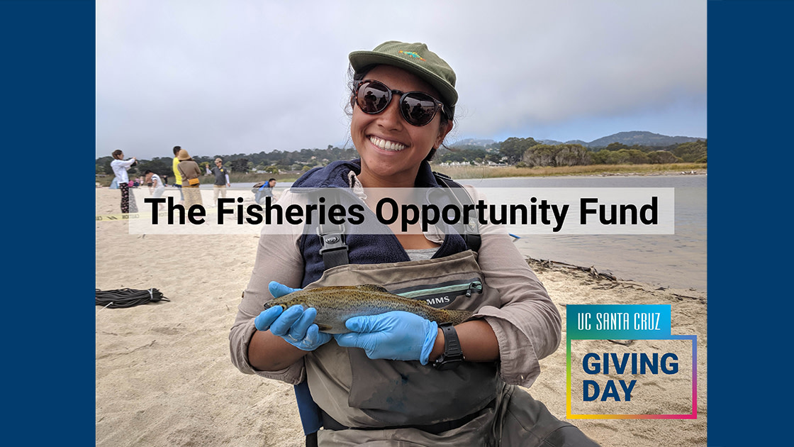 Image 1 - student holding fish on sandy shore smiling at the camera