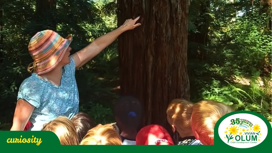 Olum teacher pointing out a detail on the tree bark to a group of children
