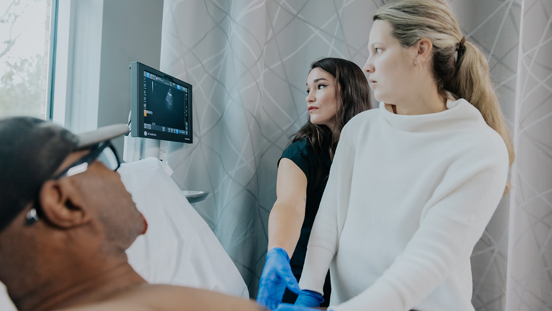Nursing student performing an ultrasound on a patient with a clinical instructor