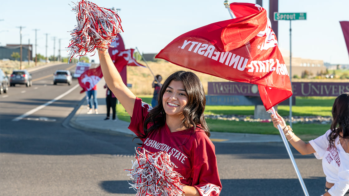 Students cheering on passing cars on campus