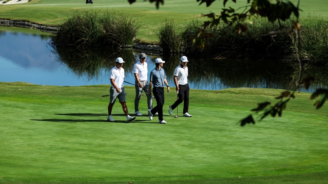 Four members from the Men’s Golf Program at UC Irvine walking across a golf course.