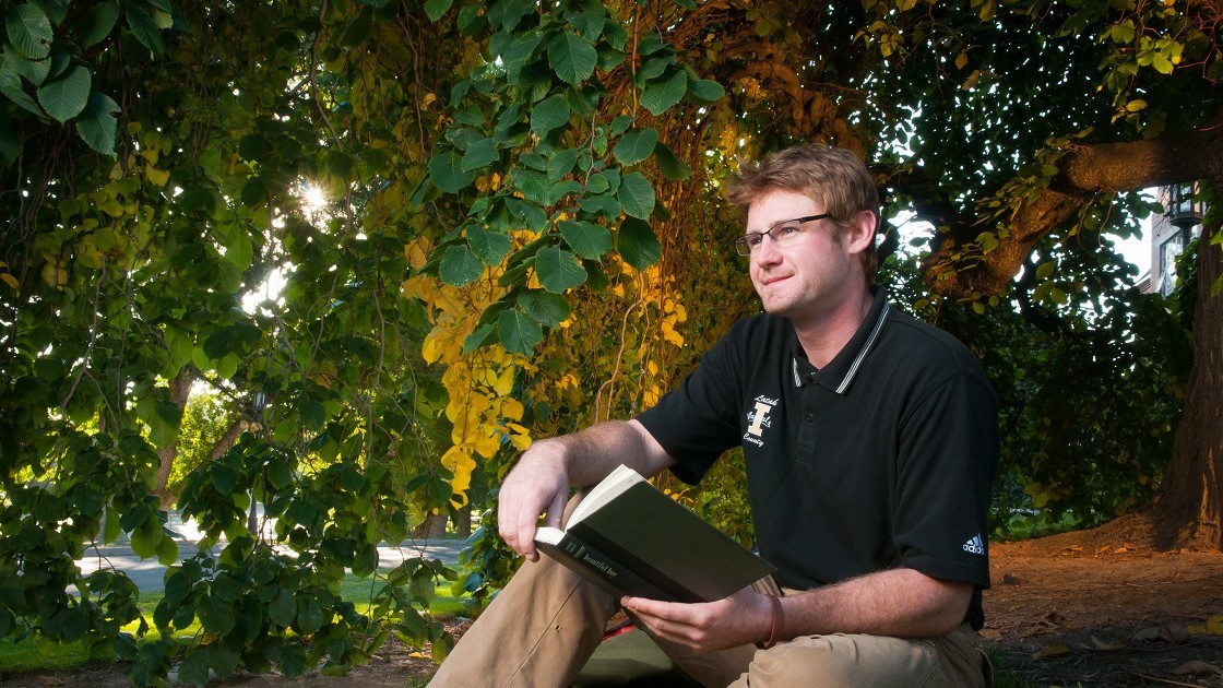 Former program Peer-Mentor reading a book on U of I campus