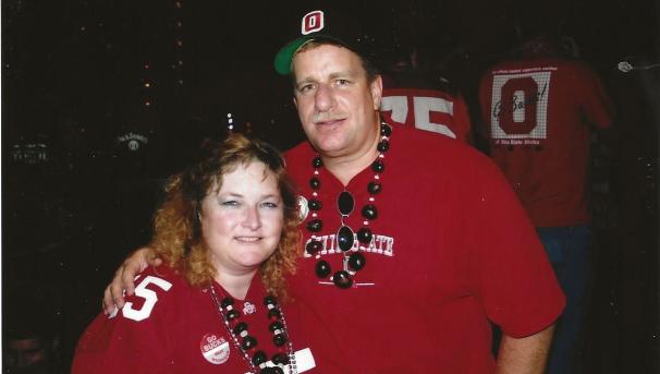 Andy and Sue Frank pose for a picture together. Both wear OSU shirts and buckeye necklaces