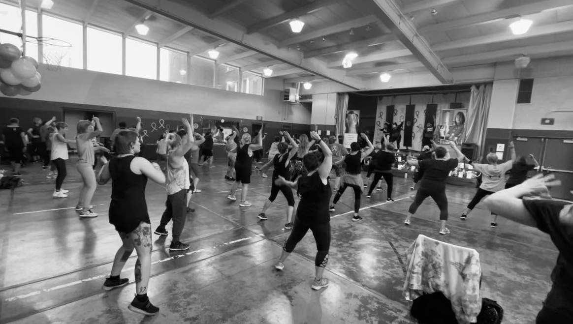 Black and white photo of group following instructor's dance moves
