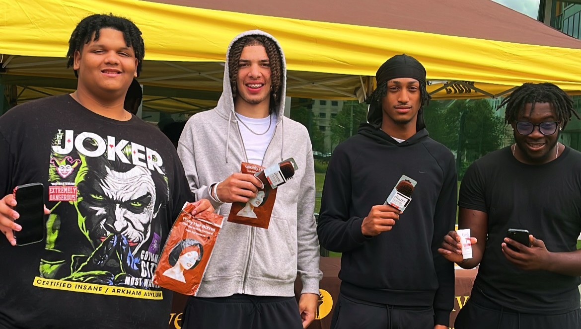 Four students holding bonnets and brushes received from a Belonging and Care pop up event.