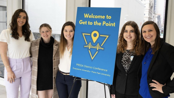 Members of PRSSA pose next to blue poster that says Welcome to Get to the Point