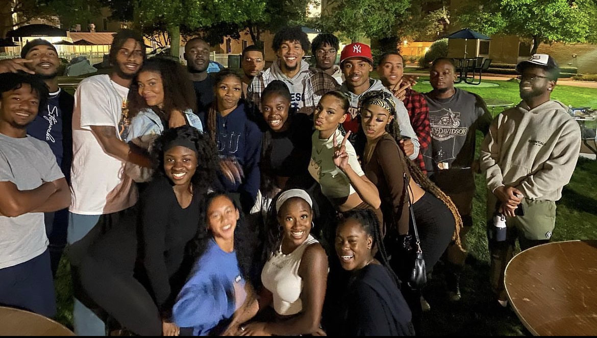 A large group of students smile at an outdoor BSU event