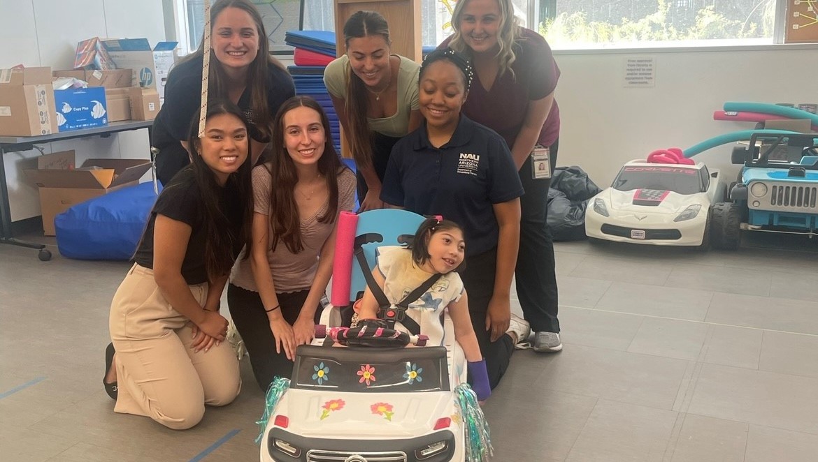 NAU Occupation Therapy Students posing with Go Baby Go recipient