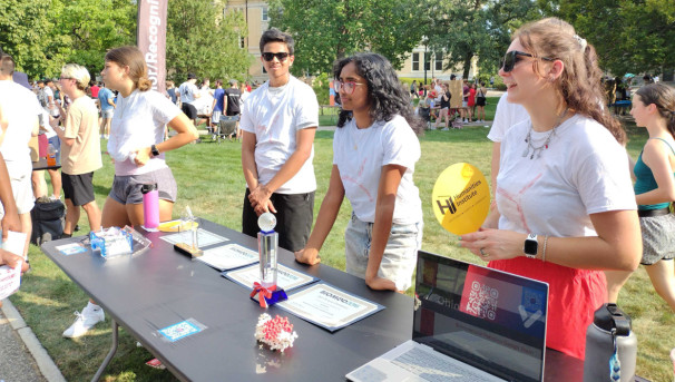 Group of students standing behind a table at involvement fair on oval