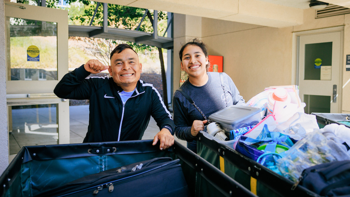 Parents and student posing for photo while moving in