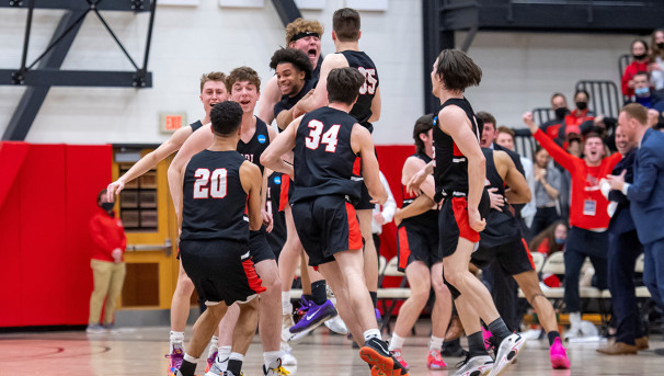 The basketball team celebrating on the court after a win.