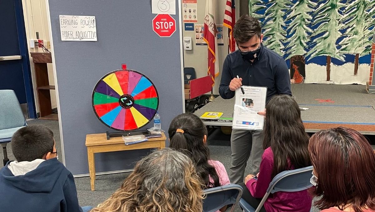 CEE CSUF Staff explaining 'Earning Power' to several families during Family Financial Fun Night