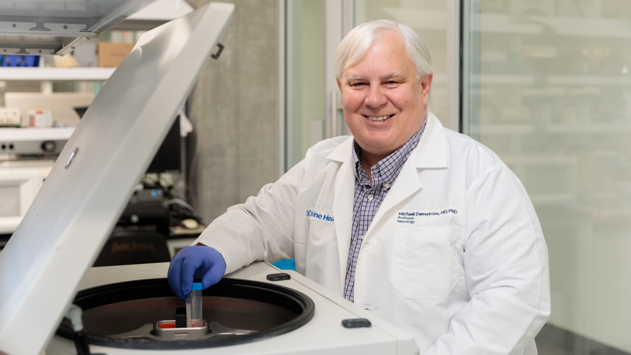 A scientist places a cancer cell sample tube into a laboratory centrifuge