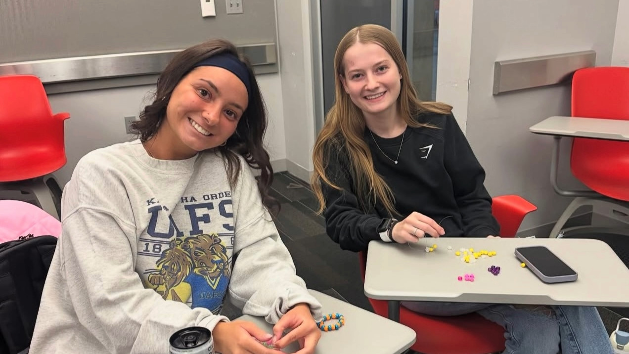 Two Dental Brigade students at a club social event making bracelets