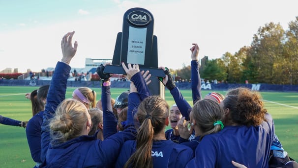 Monmouth Field Hockey players celebrate their regular season championship with trophy in the air