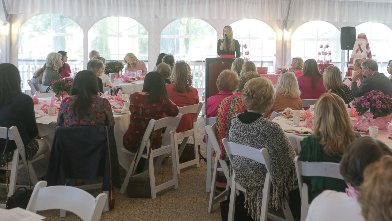 Maddie speaking to a group of people. She stands at a podium with a microphone in her hand