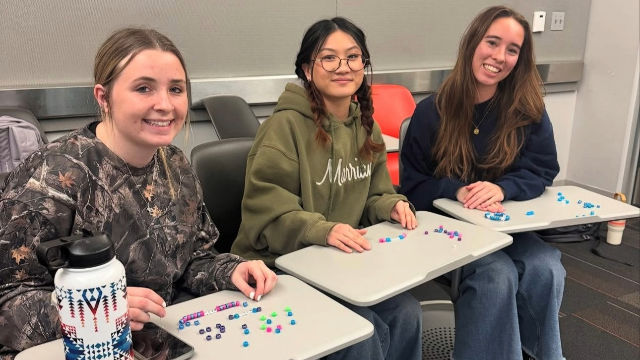 Three Dental Brigade students at a club social event making bracelets