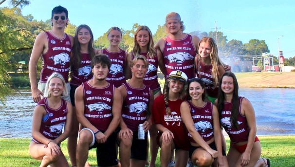 12 members of the water ski club wearing their uniforms and standing together in front of the water