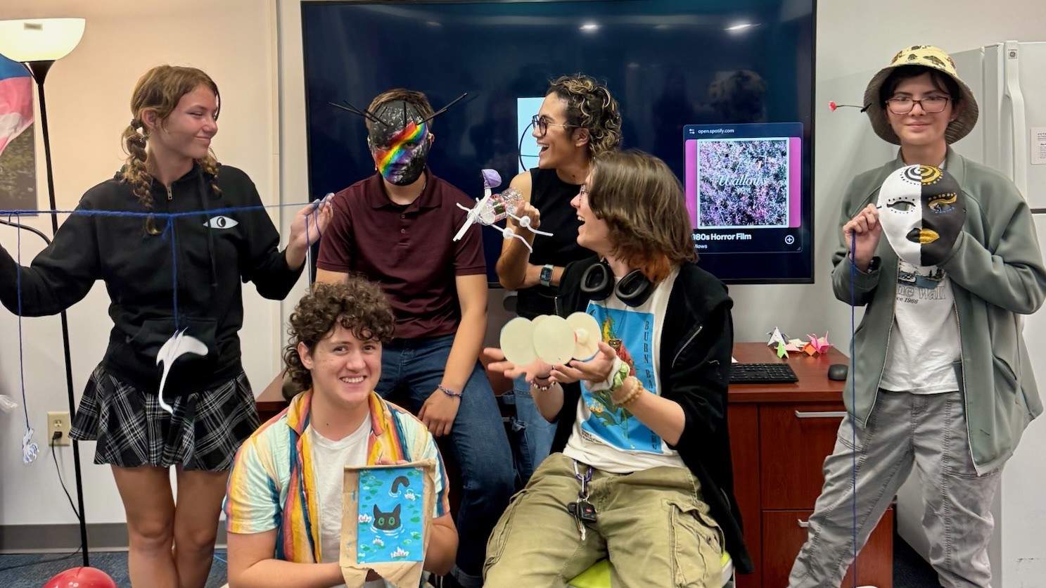Students laughing while posing for a photo with their handmade crafts