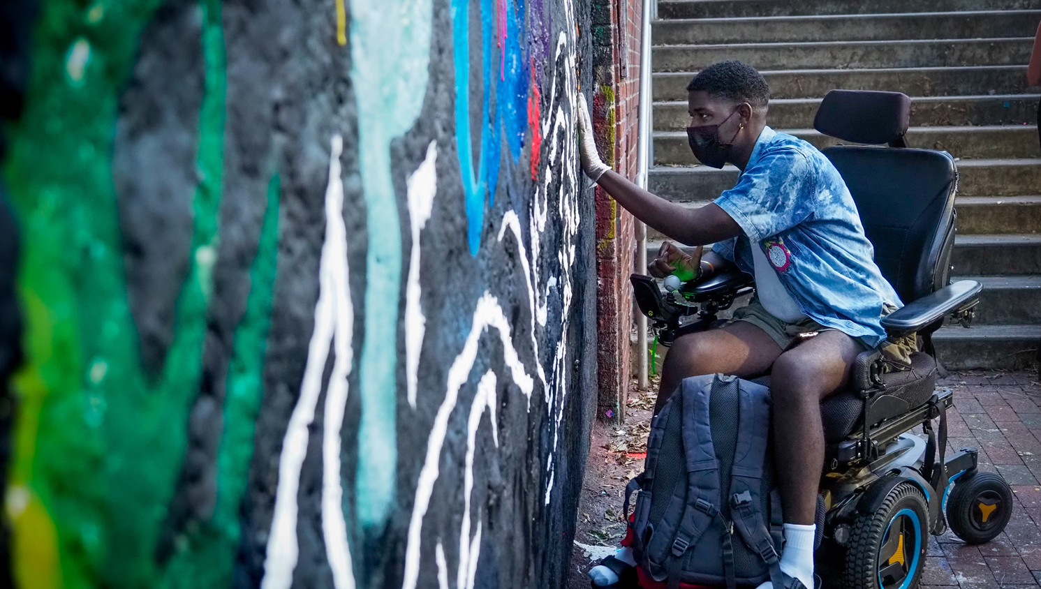 A student in a wheelchair places their handprint at the Free Expression Tunnel.