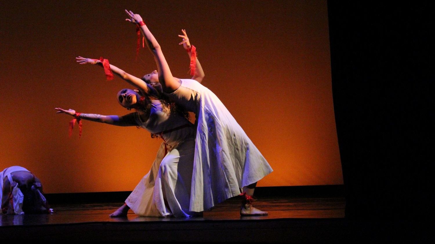 Three students modern dancing on a moodily lit stage