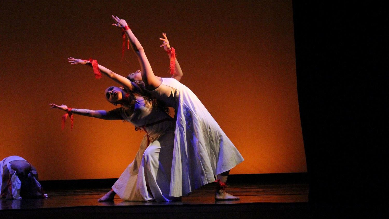 Three students modern dancing on a moodily lit stage