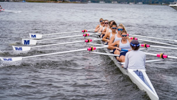 Monmouth Rowing student-athletes carrying an eight-person boat into the water for competition.