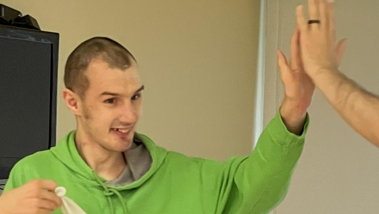 Eric sitting in the backseat of a car. Outside is green grass and sparce trees