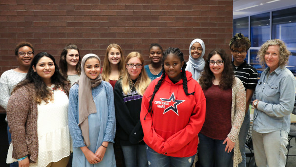 The group of 10 girls posing for a picture against a brick wall