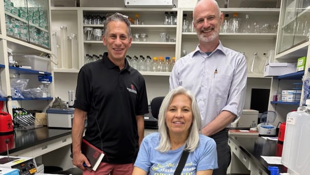 Seth & Lori Cramer posing with Dr. Kolb in his lab for ALS research
