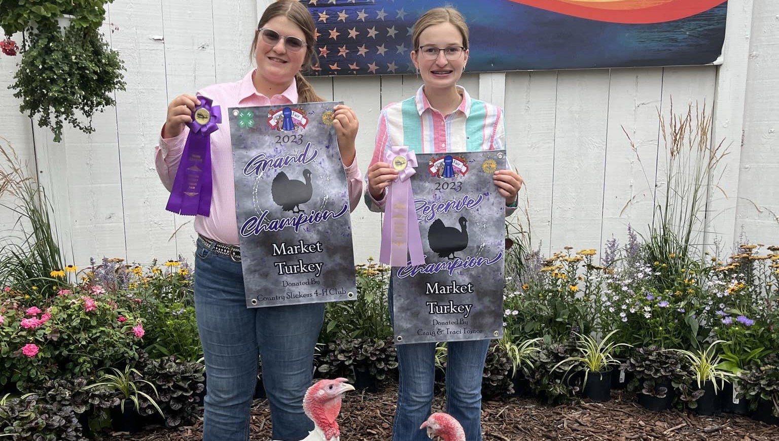 Two individuals holding Grand Champion Market Turkey signs with ribbons
