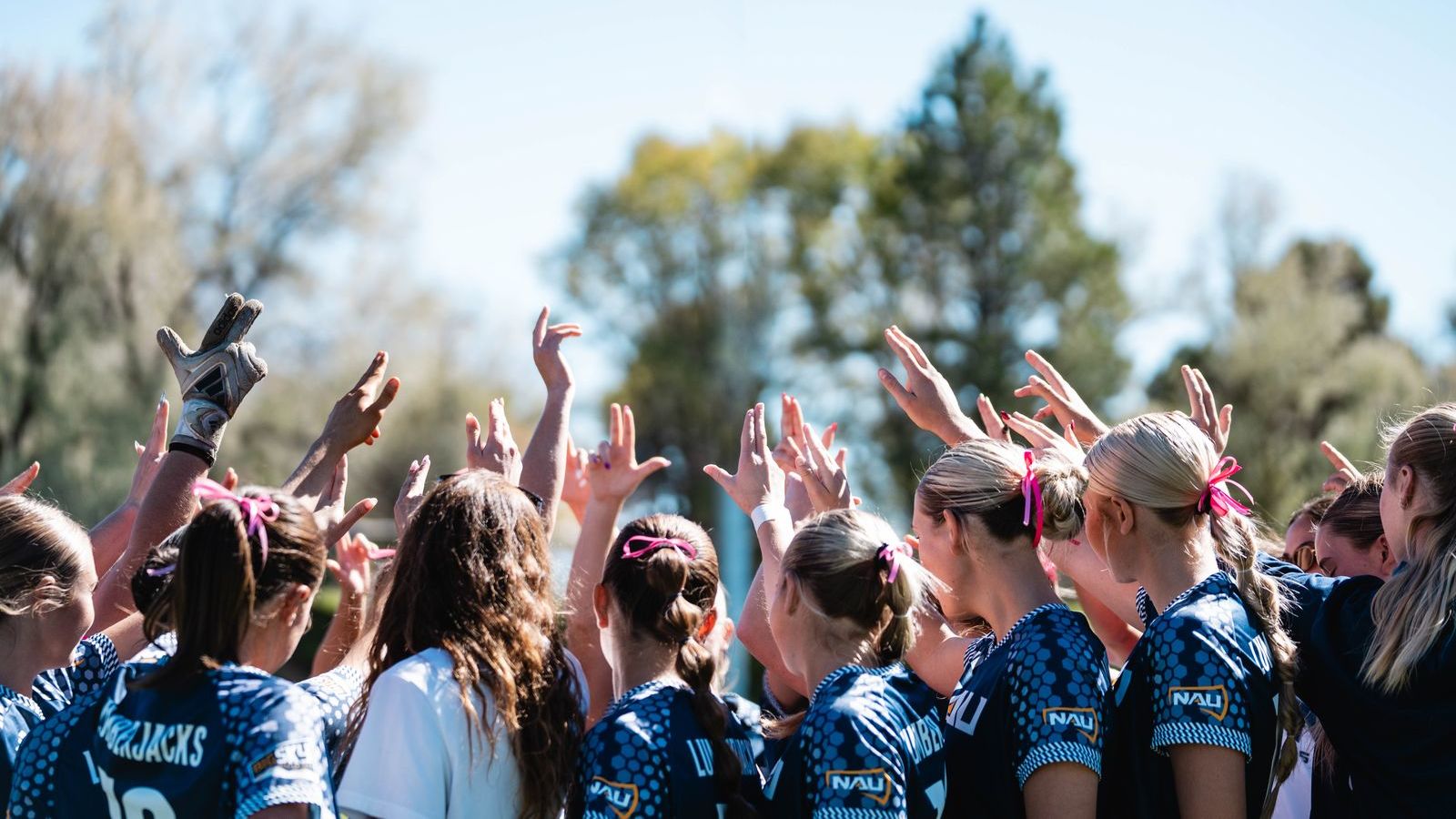 Two women pose together wearing NAU gear during a meet.