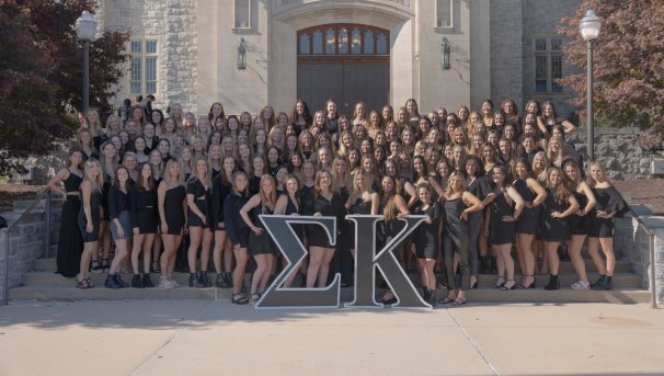 members of sigma kappa sorority stand with their letters smiling in front of burruss hall
