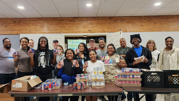 A group of eleven people, sitting on some rocks in front of the ocean and smiling at the camera.