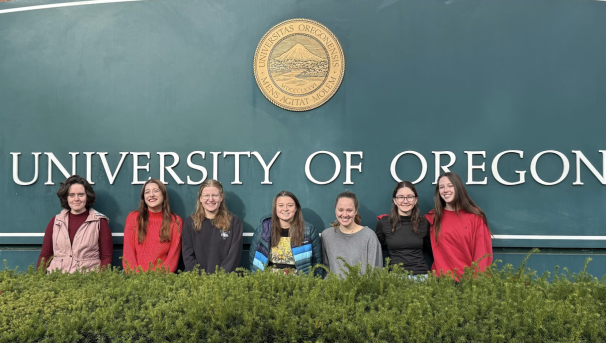 Women in Graduate Sciences officers looking happy posed in front of the University of Oregon sign.