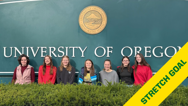 Women in Graduate Sciences officers looking happy posed in front of the University of Oregon sign.