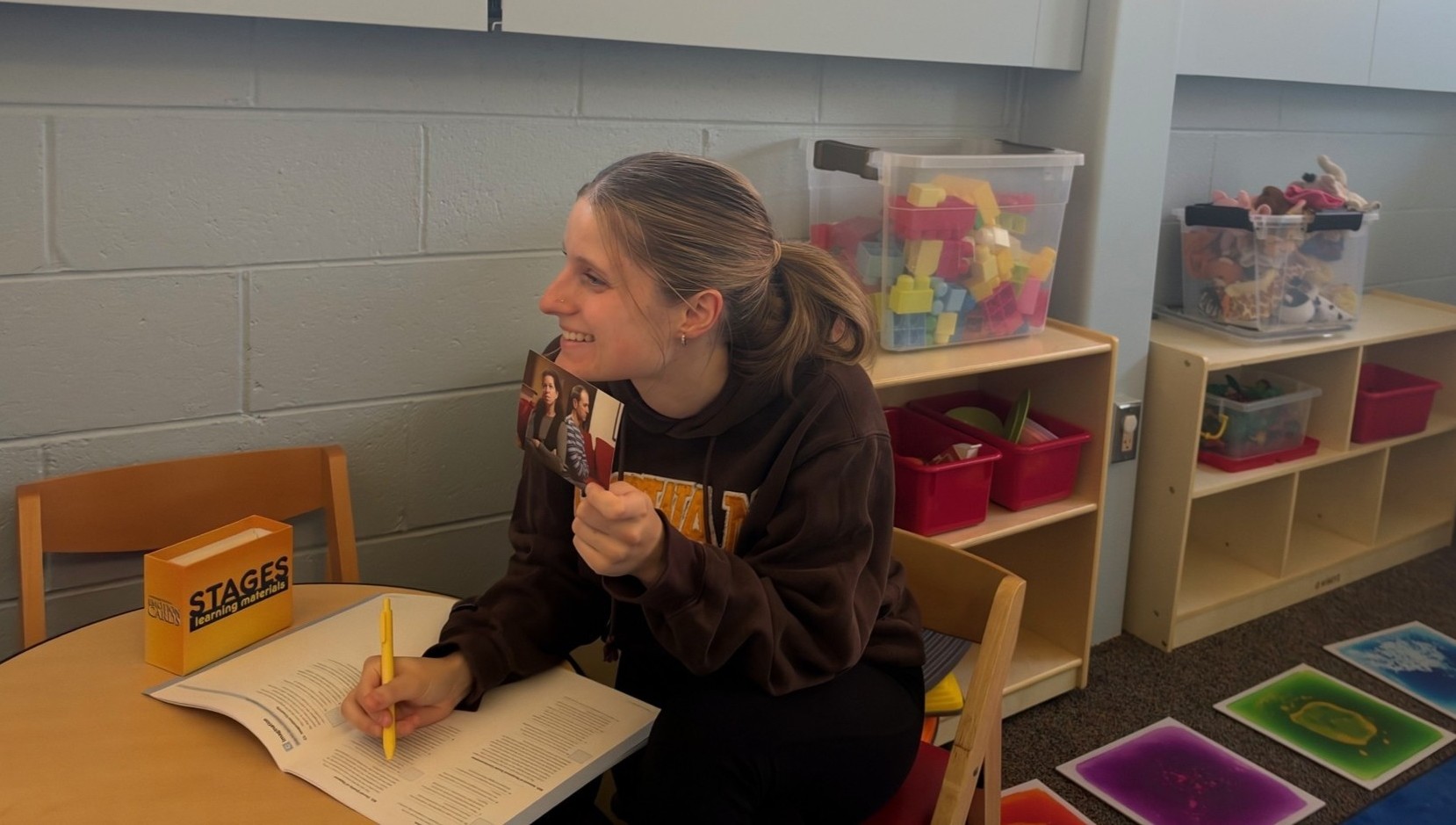 Rowan student holding up an image and taking notes while providing therapy in the clinic.