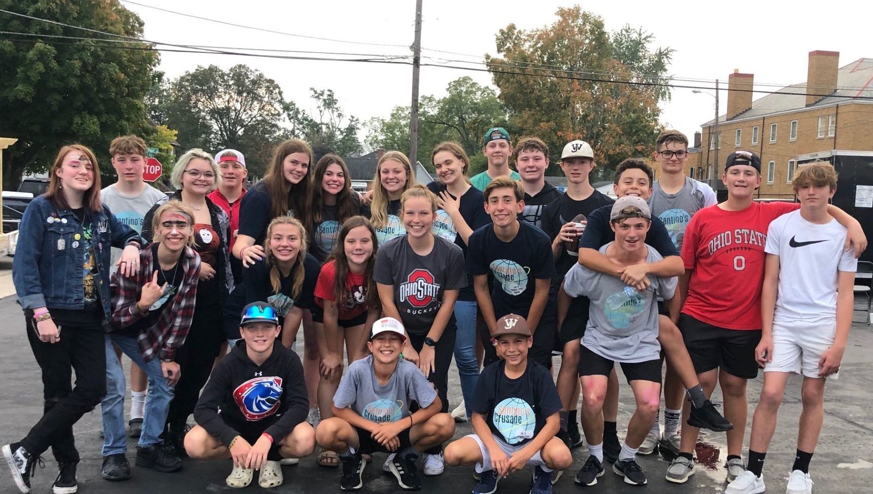 Group of young individuals smiling for a photo while holding Santino's Crusade signs