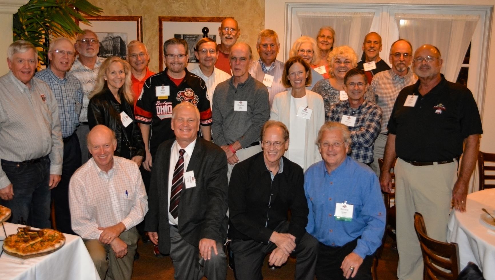 A group of alums stand together at a dinner, smiling towards the camera