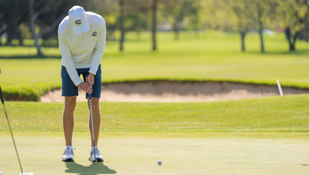 Men’s Golf Team member putting the ball.